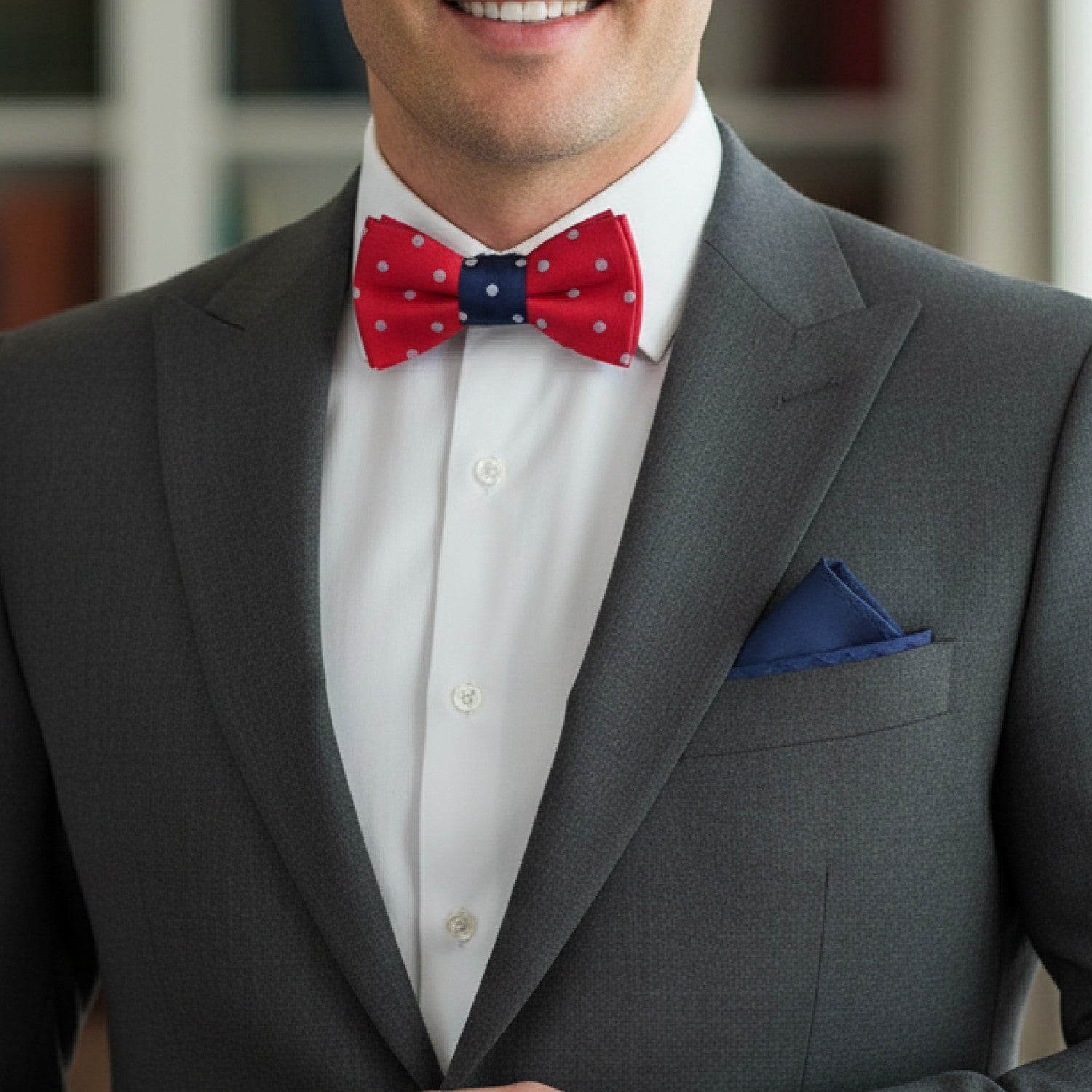 Man wearing a gray suit with a red and blue bow tie and white shirt.