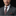 Man wearing a gray suit with a rust brown striped tie and pocket square on a black background
