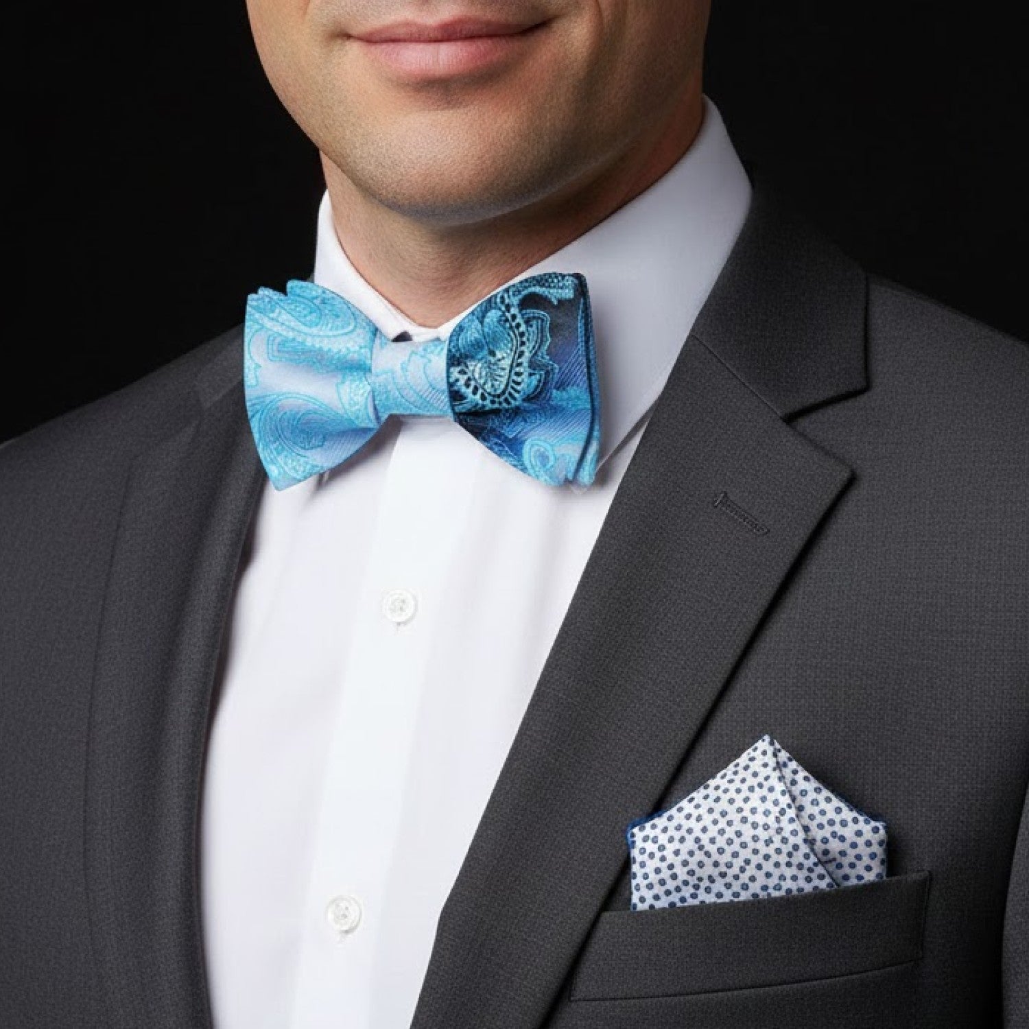 Man wearing a gray suit with a blue patterned bow tie and matching pocket square.