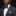 Man wearing a gray suit with a blue bow tie and pocket square on a black background