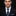 Man wearing a black suit with a blue striped tie against a black background