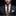 Man wearing a dark suit with a patterned tie and pocket square against a black background