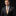 Man wearing a dark suit with a patterned tie and pocket square on a black background