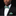 Man wearing a black suit with a green and blue checkered bow tie and pocket square.