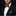 Man wearing a black suit with a red, orange and grey patterned bow tie and matching pocket square on a dark background