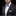 Man wearing a black suit with a purple bow tie and pocket square on a black background