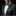 Man wearing a black suit with a green bow tie and pocket square on a black background