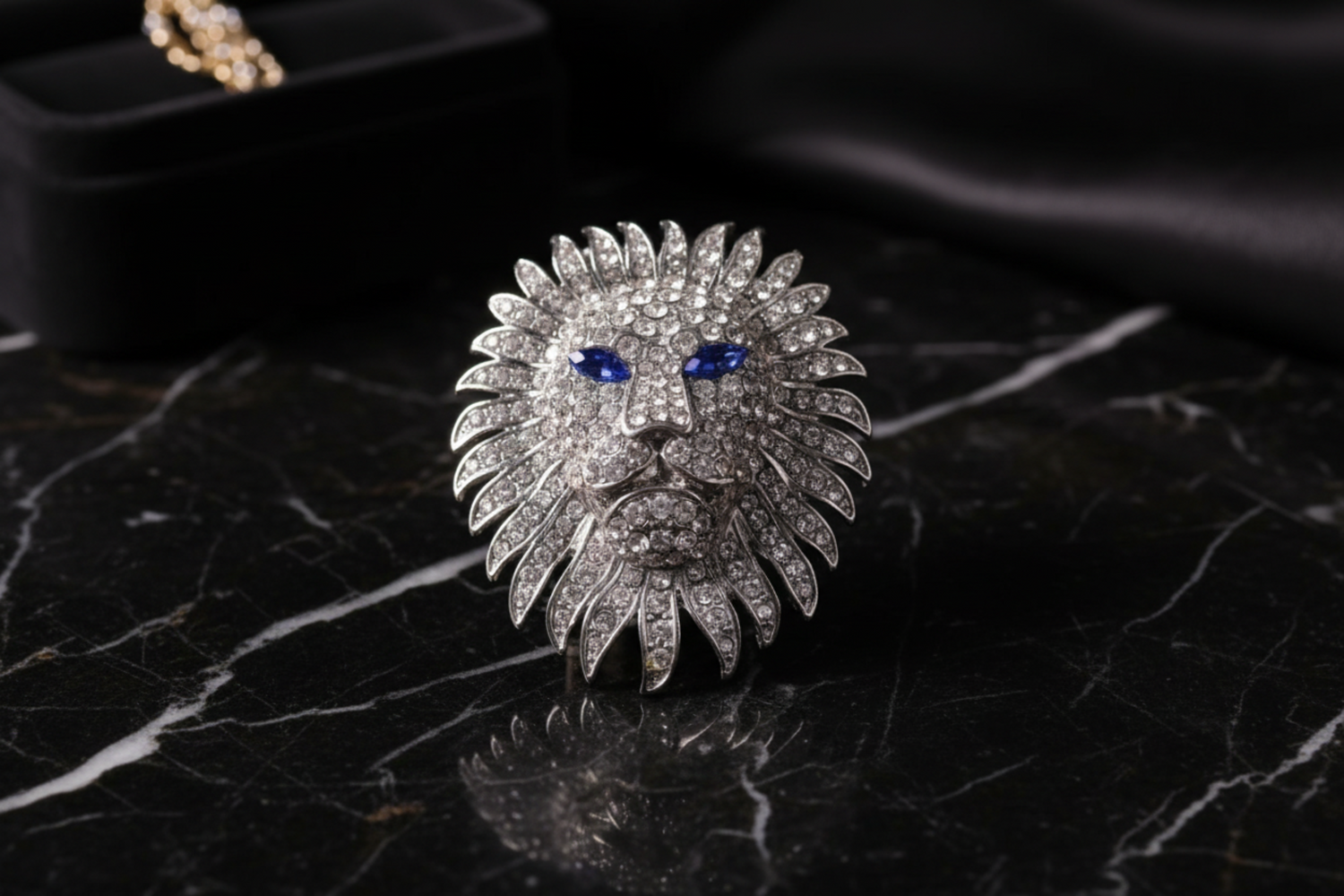 Silver lion head brooch with blue gemstones on a light gray background