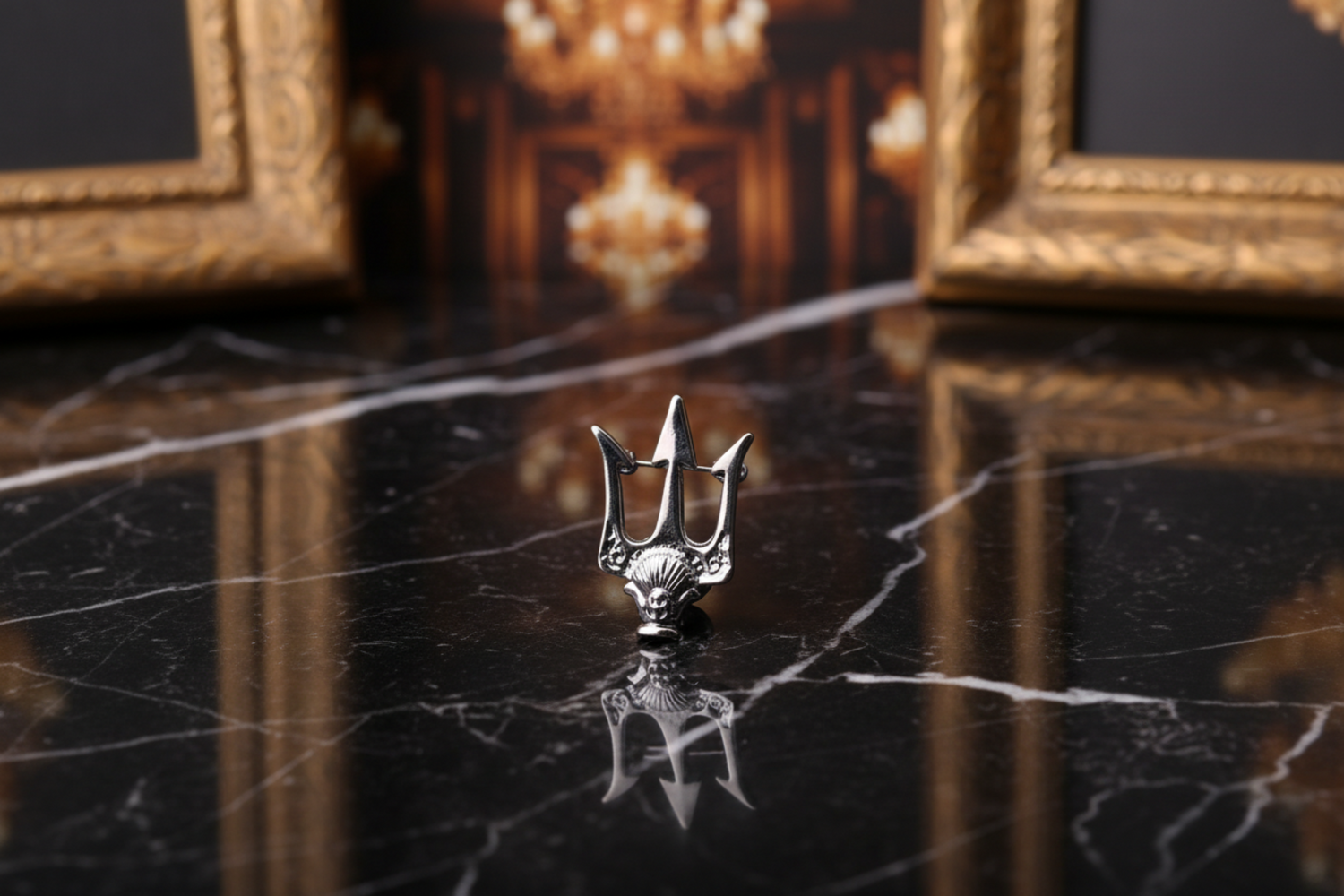 A gold trident-shaped lapel pin displayed on a grey surface with flowers in the background.