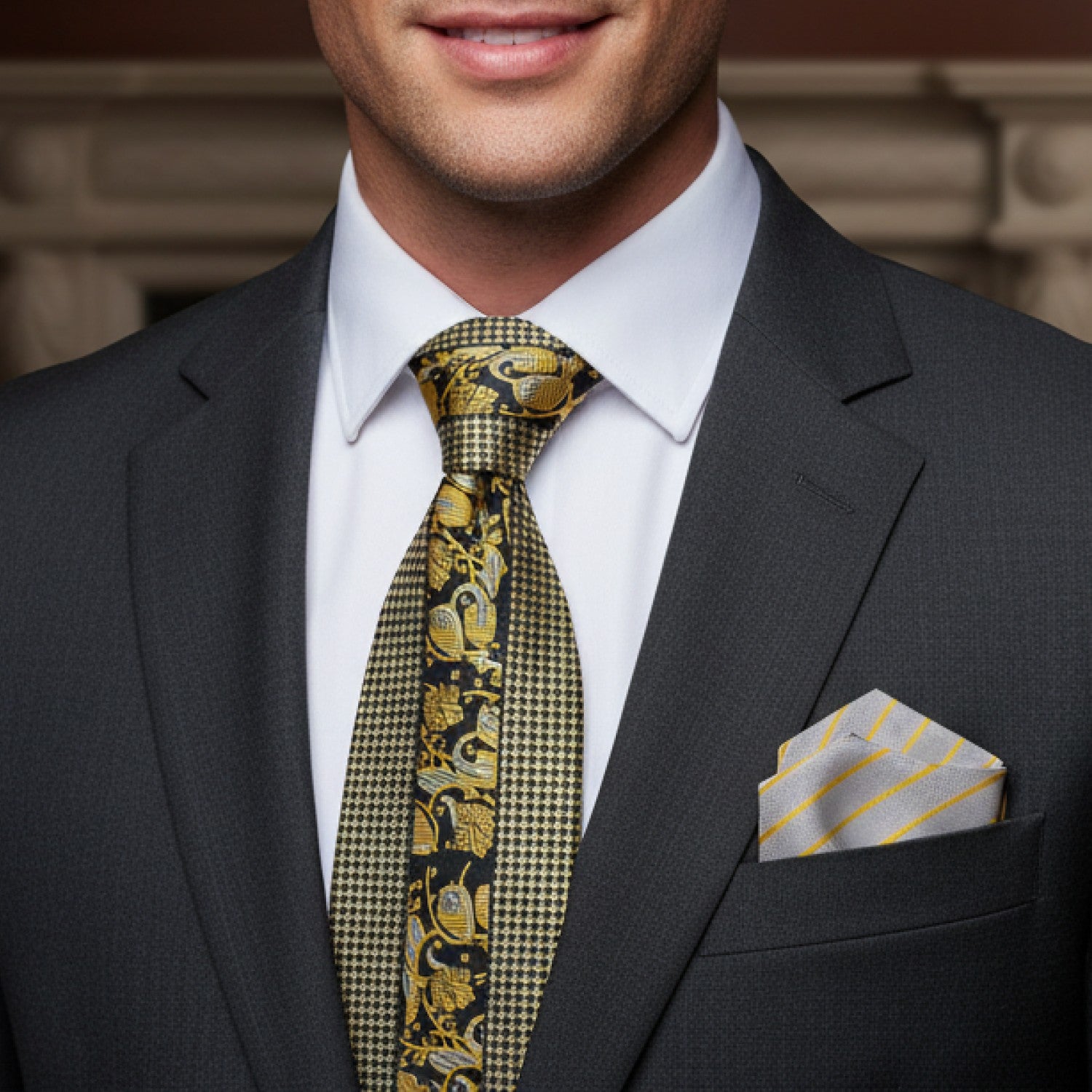 Man wearing a gray suit with a patterned yellow tie and matching pocket square.