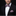 Man wearing a black suit with a pink bow tie and pocket square on a black background