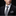 Man wearing a black suit with a patterned tie and pocket square on a black background