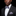 Man wearing a black suit with a white shirt and patterned bow tie and pocket square on a black background