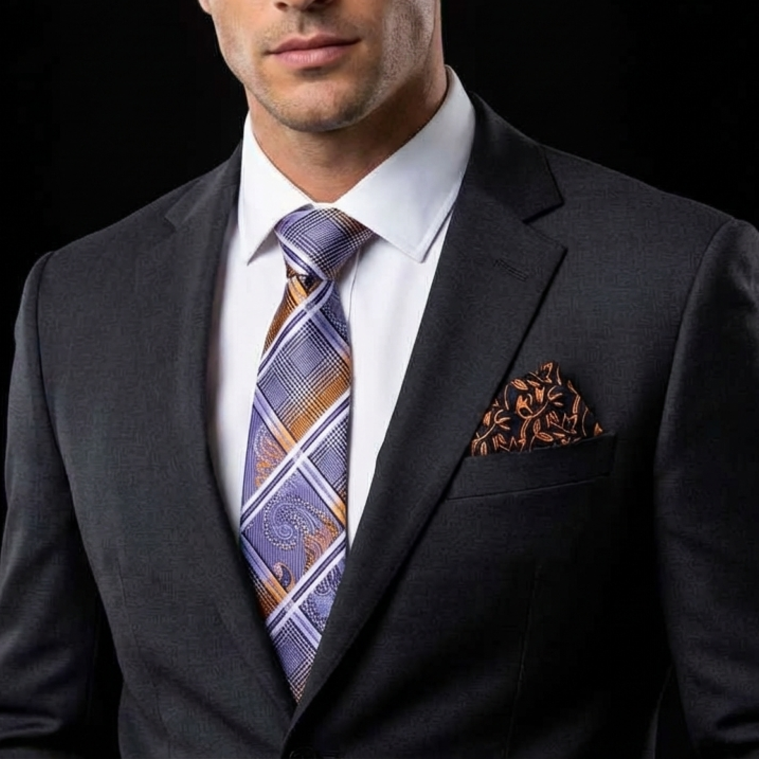 Man wearing a dark suit with a patterned tie and pocket square against a black background
