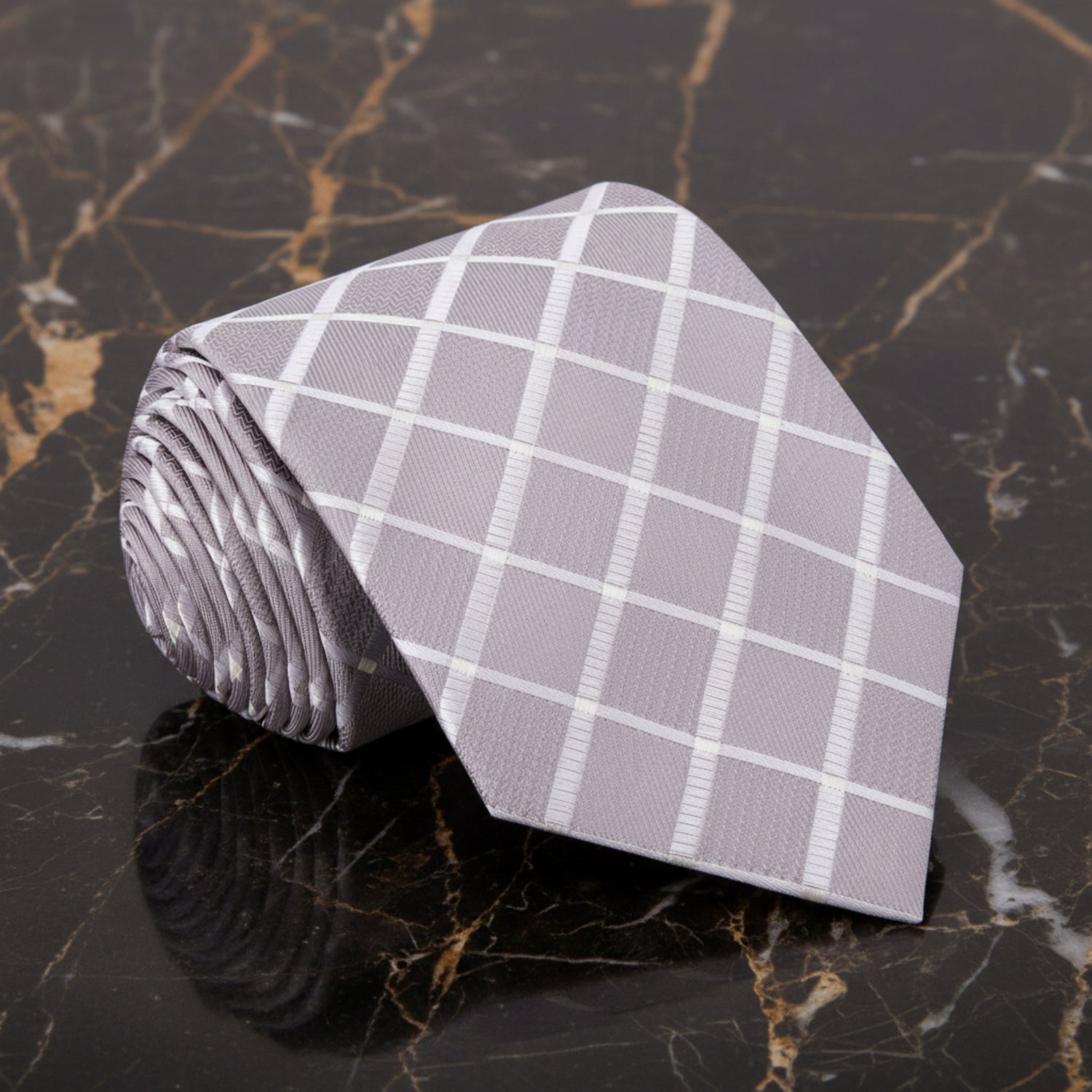 Roll of gray checkered fabric on a dark marble surface