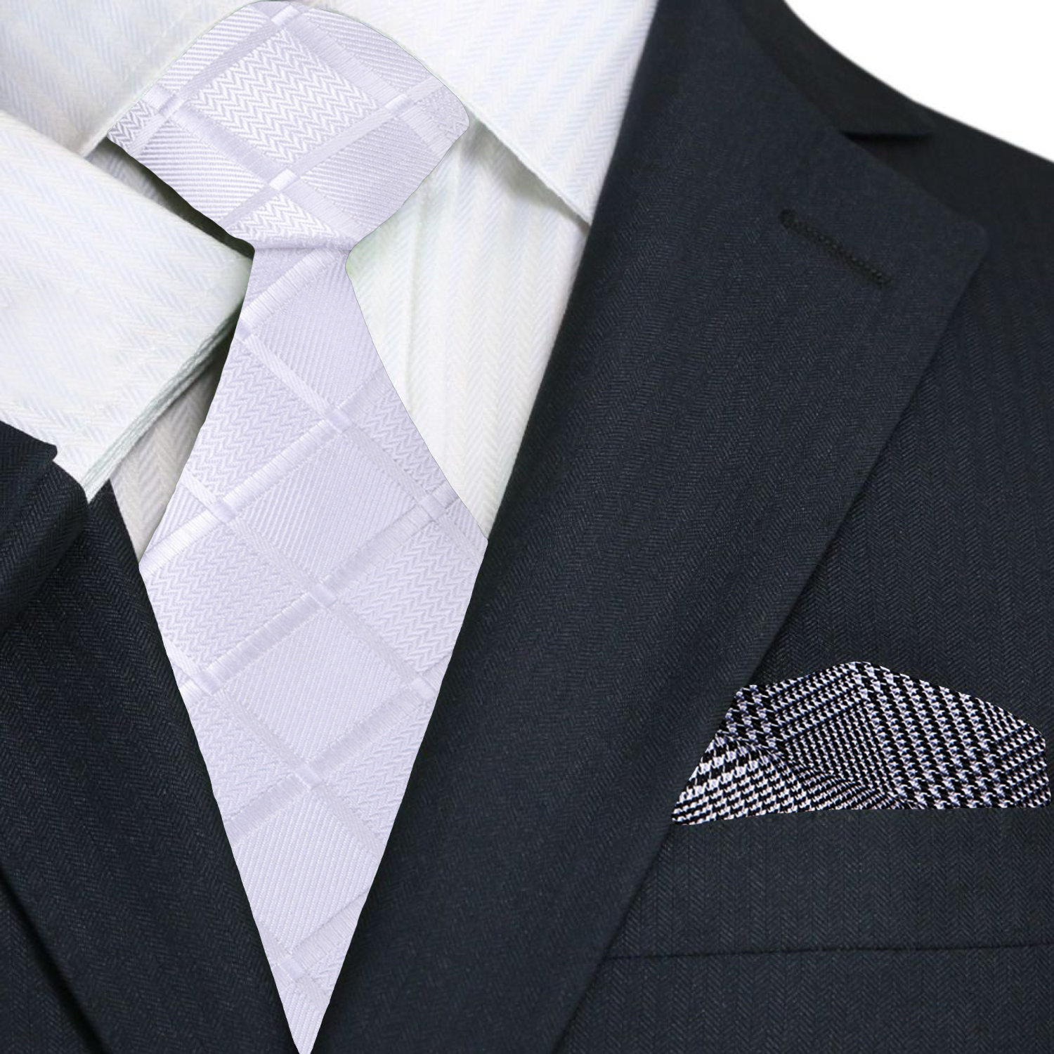 Black suit with white dress shirt, light white check tie, and patterned grey and black plaid pocket square.