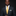 Man wearing a dark suit with a yellow tie and patterned pocket square on a black background