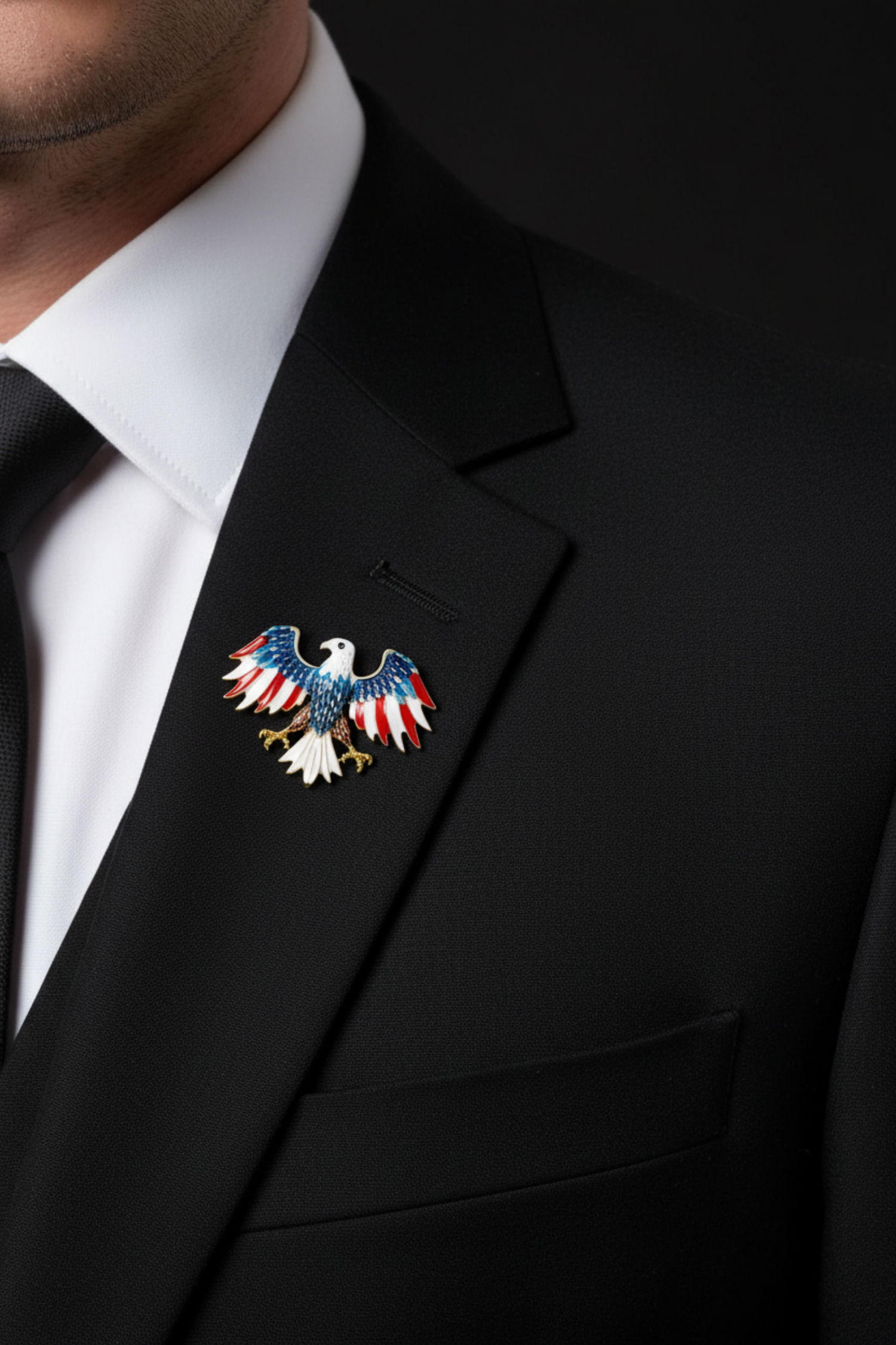 An eagle brooch with spread wings, featuring a white head and tail, red and white striped wings, a blue upper body, and brown and gold details on the legs and talons, set against a plain white background.