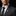 Man wearing a dark suit with a decorative star pin on a black background