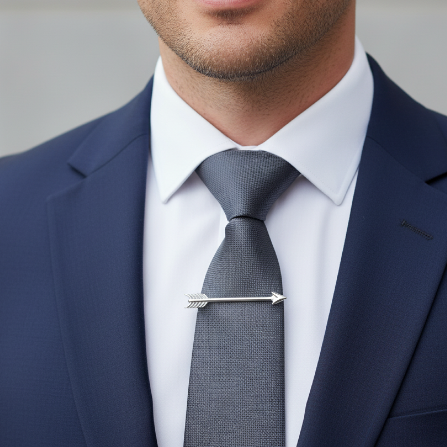 Man wearing a navy suit with a gray tie and white shirt.
