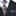 Black suit with a patterned purple and gold paisley and plaid tie and pocket square