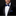 Man wearing a black tuxedo with a blue bow tie and pocket square on a dark background
