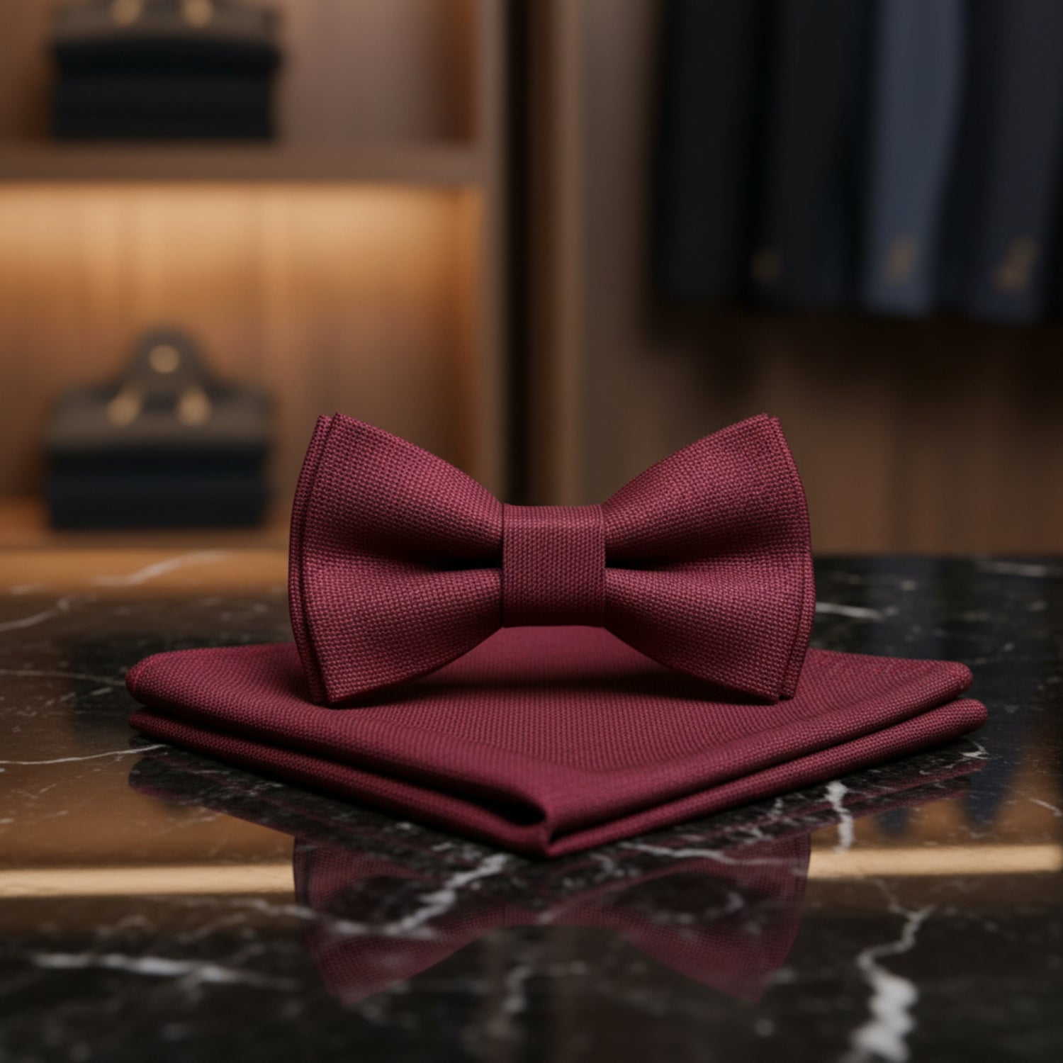 A matching burgundy bow tie and pocket square set with a subtle woven texture, displayed on a clean white background.
