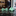 Two green bow ties on a reflective surface with a blurred background of a store interior.