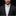 Man wearing a black suit with a white shirt and tie on a dark background