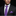 Man wearing a black suit with a purple tie and pocket square on a dark background