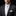 Man wearing a black suit with a white shirt and tie on a black background