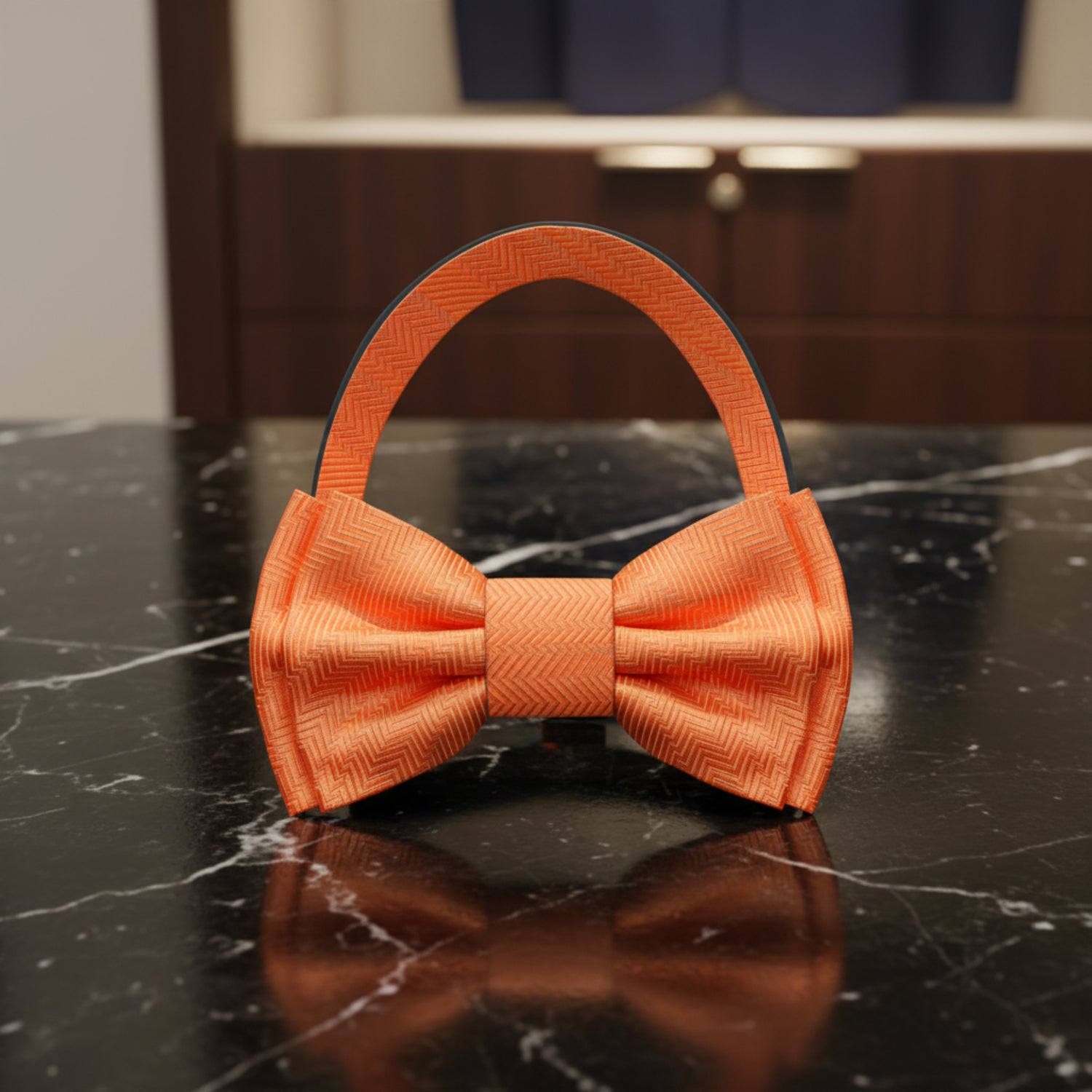 Orange bow tie on a black marble surface with decorative background