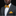 Man wearing a gray suit with a yellow bow tie and pocket square on a black background