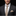 Man wearing a dark suit with a beige tie and pocket square on a black background