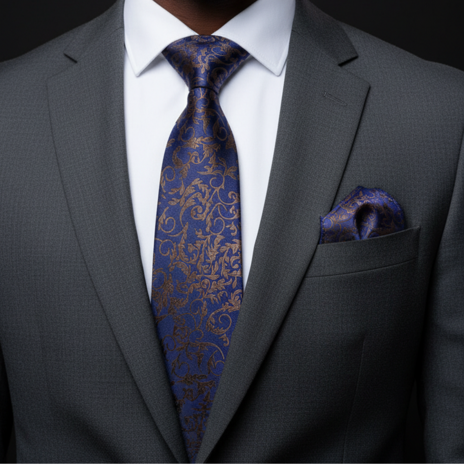 Gray suit with a blue patterned tie and pocket square on a black background