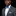 Man wearing a gray suit with a blue and green bow tie and pocket square on a black background