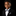 A young boy wearing a black formal suit jacket, white dress shirt, black and white polka dot bow tie, and matching pocket square, photographed against a solid black background.