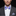 Man wearing a gray suit with a blue and white patterned bow tie and pocket square on a black background