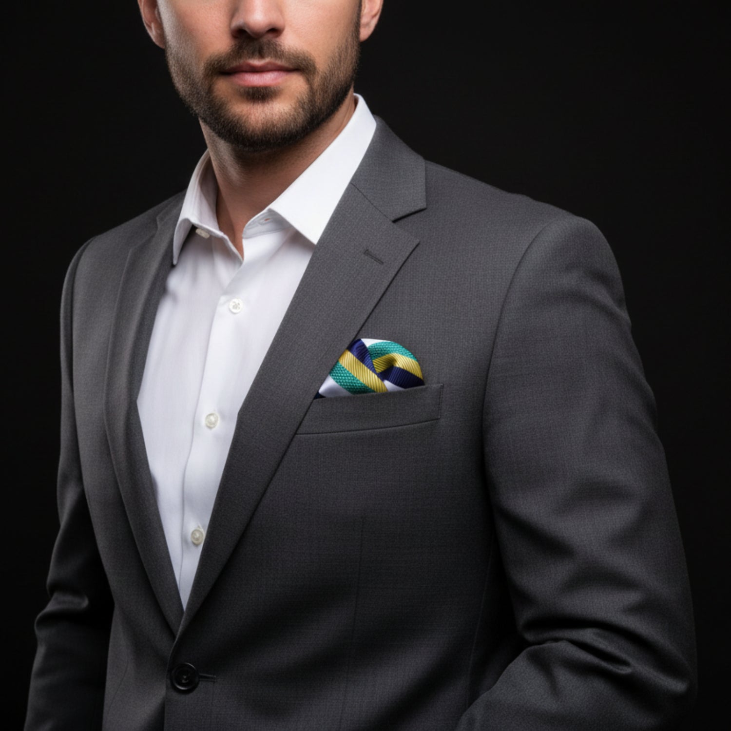 Man wearing a gray suit with a patterned pocket square on a black background