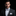 Man wearing a black suit with a colorful bow tie and pocket square on a black background