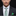 Man wearing a dark suit with a white shirt, green tie, and matching pocket square on a black background