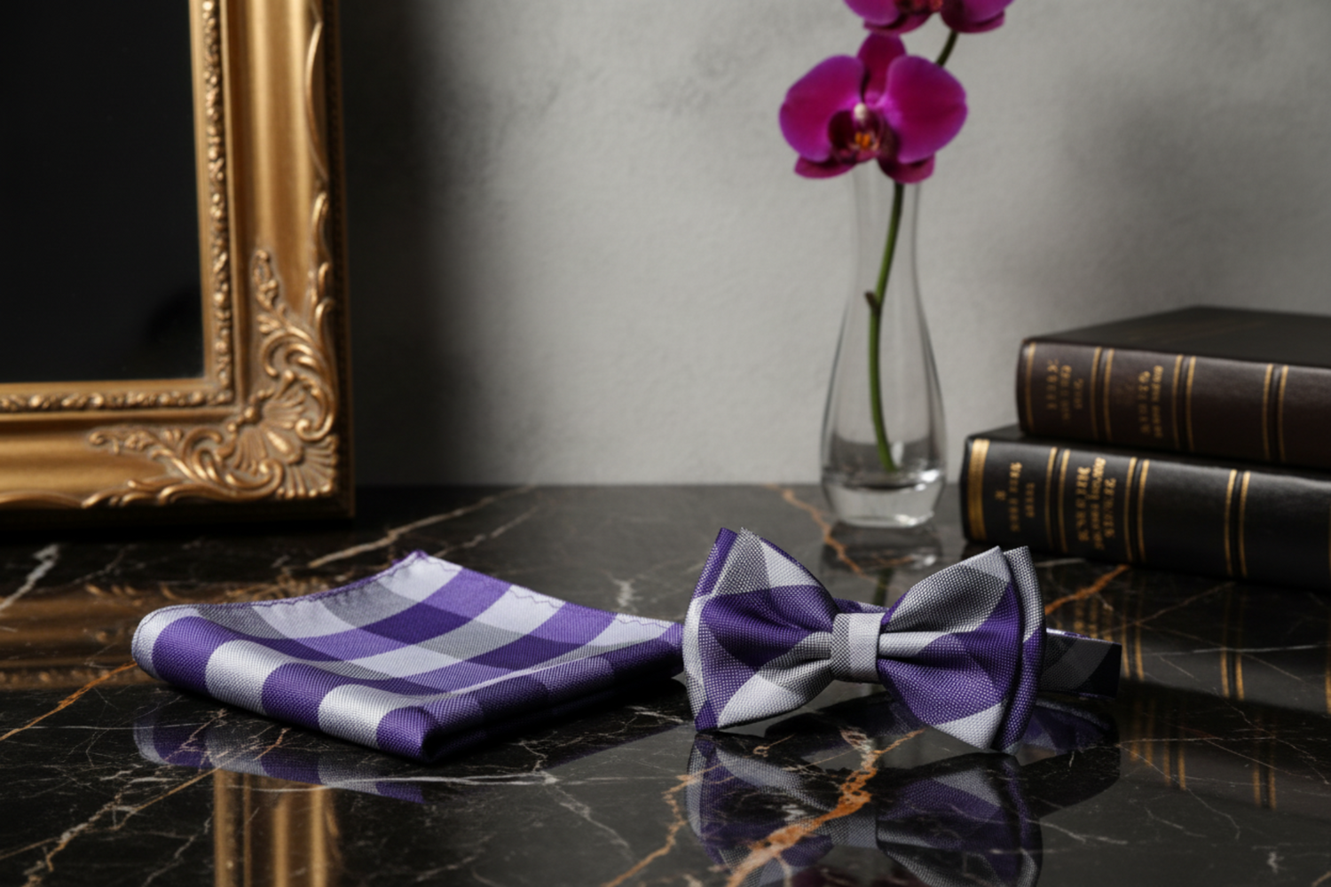 A matching men's accessory set featuring a folded pocket square and a self-tie bow tie, both in a purple, gray, and white checkered pattern, displayed on a clean white background.