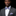Man wearing a gray suit with a floral bow tie and pocket square on a black background