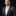 Man wearing a gray suit with a patterned tie and pocket square on a black background
