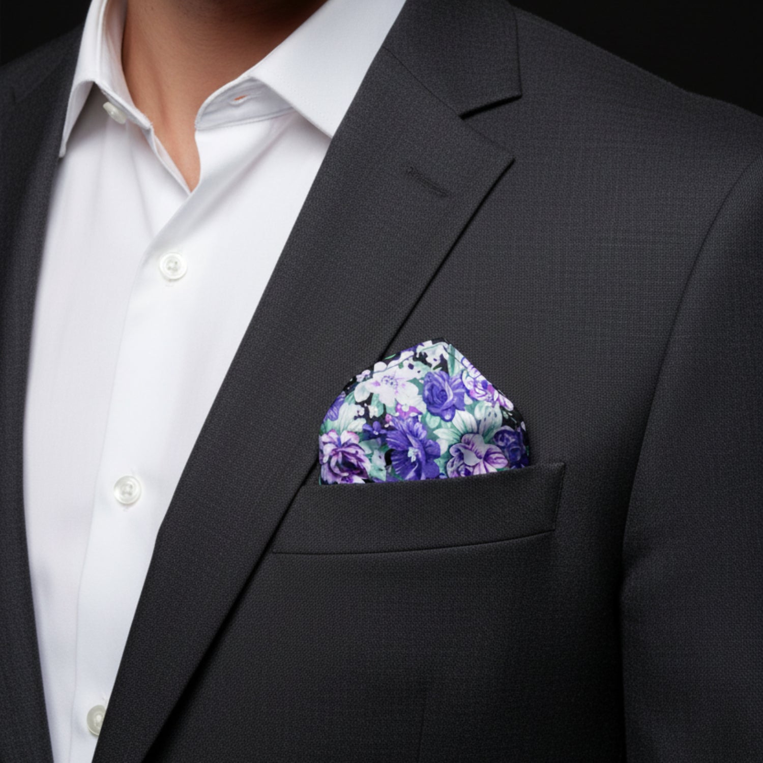 Man wearing a black suit with a floral pocket square and white shirt.