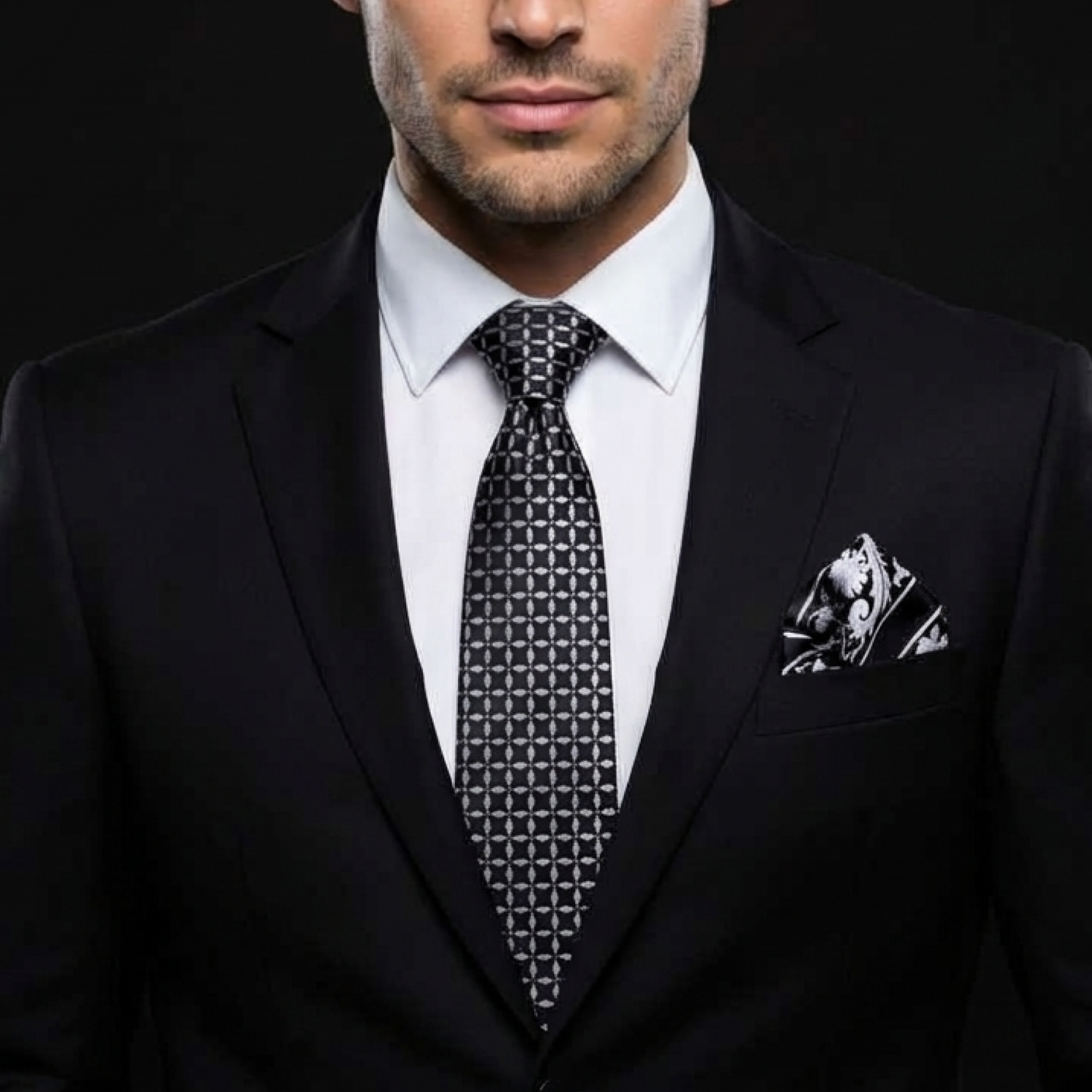 Man wearing a black suit with a patterned tie and pocket square on a dark background