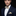 Man wearing a navy suit with a yellow and blue striped bow tie and pocket square on a black background
