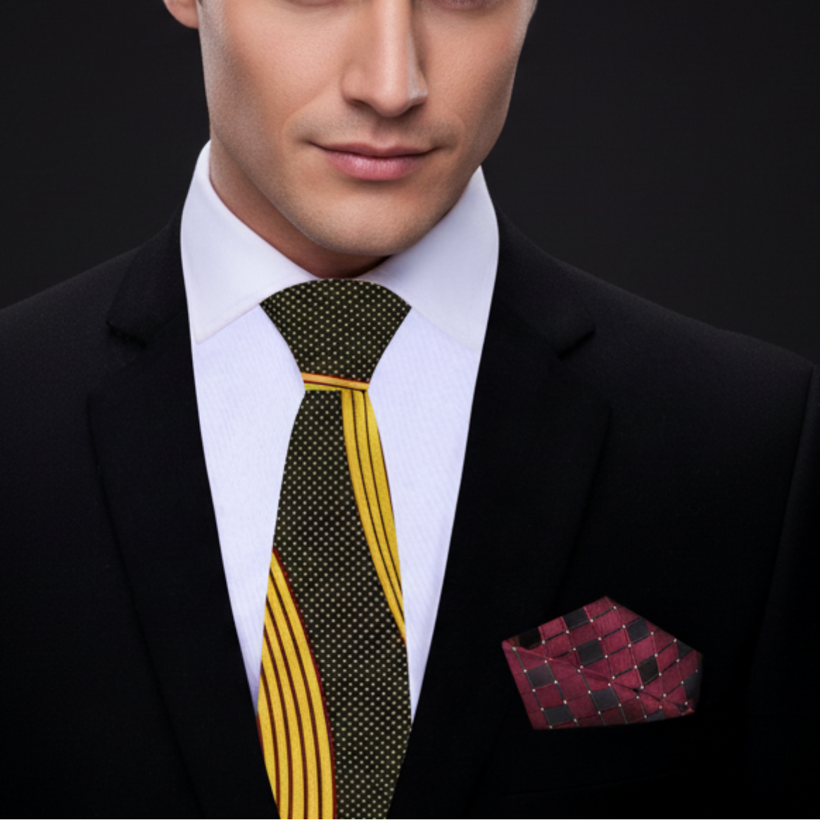 Man wearing a black suit with a yellow and green patterned tie and a red pocket square.