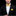 Man wearing a black suit with a yellow bow tie and pocket square on a black background