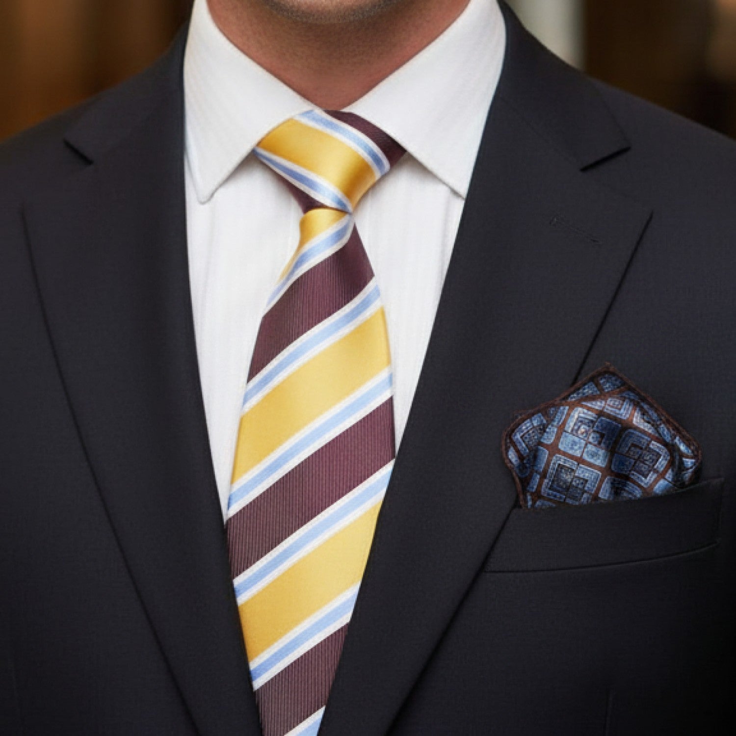 Man wearing a dark suit with a colorful striped tie and patterned pocket square.